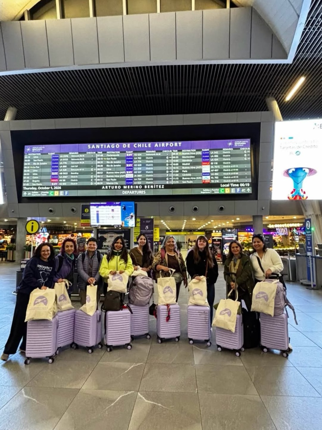 Grupo de viajeras en el aeropuerto de Santiago con sus maletas lila